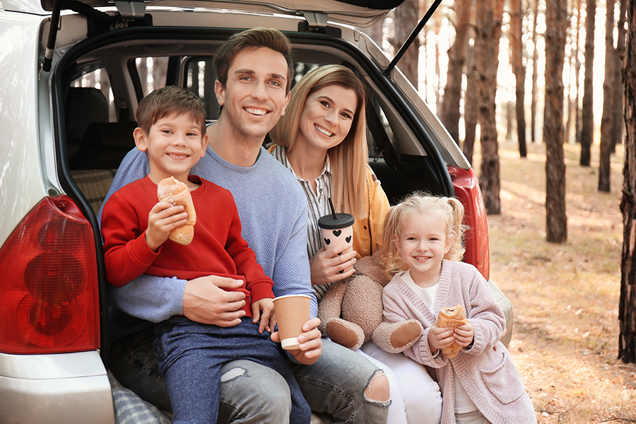 Personal Insurance - Young Couple with Their Young Children Having Lunch While Sitting in the Back of the Car